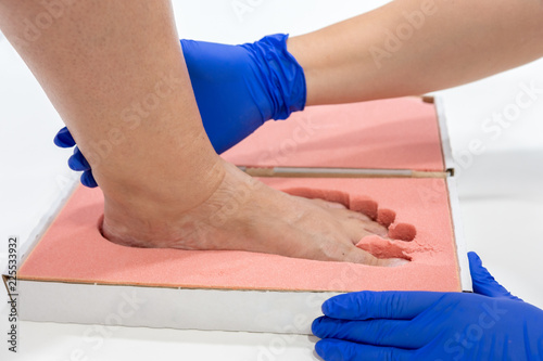 Female chiropodist, attending elder in a clinic and performing treatments podiatric, for the realization of insole for feet