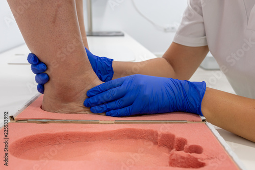 Female chiropodist, attending elder in a clinic and performing treatments podiatric, for the realization of insole for feet
