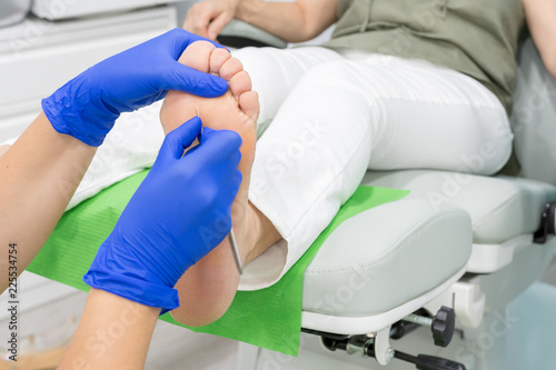 Female chiropodist, attending elder in a clinic and performing podiatric treatments