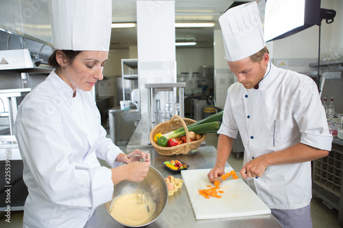 happy chefs and assistant in apron working at restaurant kitchen