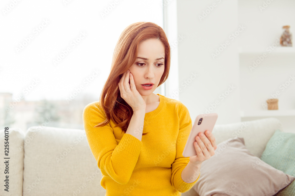 Worried woman look on screen of smartphone, touch palm on cheek Worried woman look on screen of smartphone, touch palm on cheek