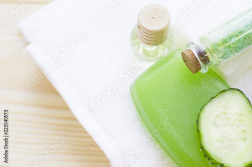 Cucumber home spa and hair care concept. Sliced cucumber, bottles of oil, soap, jar of mask, bathroom towel. White board background