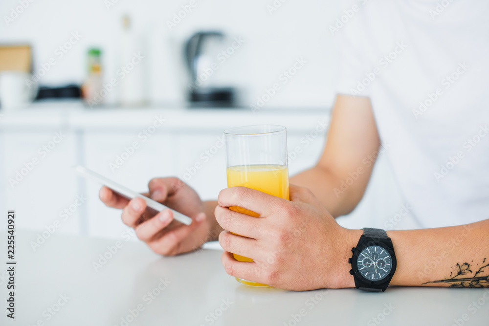 close-up partial view of young man holding glass of juice and using smartphone close-up partial view of young man holding glass of juice and using smartphone