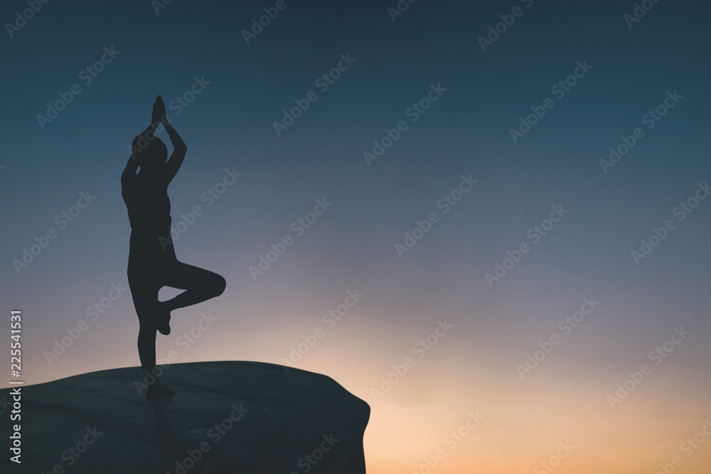 silhouette of woman doing yoga on rock