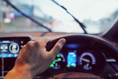 Man hands driver on steering wheel of a modern car with Car dashboard on street background.Traffic jam on rush hour in the city.Transport,Vacation,Holiday,Travel and Automobile Concept.