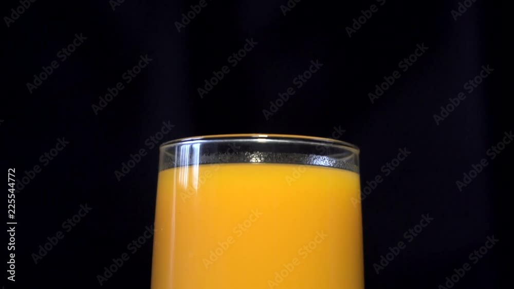 Pouring orange and yellow juice into a glass beaker. Behind the black background. A thin stream of juice is poured into a glass. Orange juice, pumpkin juice, mango juice, multifruit juice. 4K Pouring orange and yellow juice into a glass beaker. Behind the black background. A thin stream of juice is poured into a glass. Orange juice, pumpkin juice, mango juice, multifruit juice. 4K