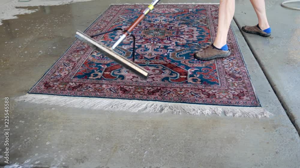 Using a squeegee to flush water off a newly cleaned oriental carpet