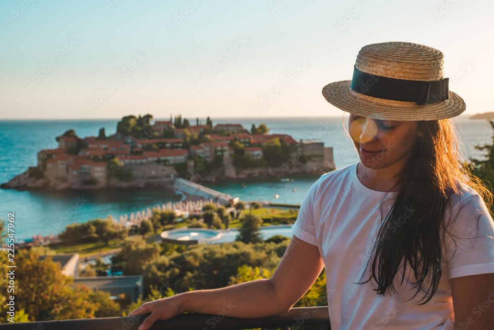 young adult woman walking on sunset. sveti stefan island on background
