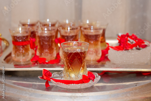 Vászonkép Set of traditional tea in eastern glass on the silver salver on the white tablec