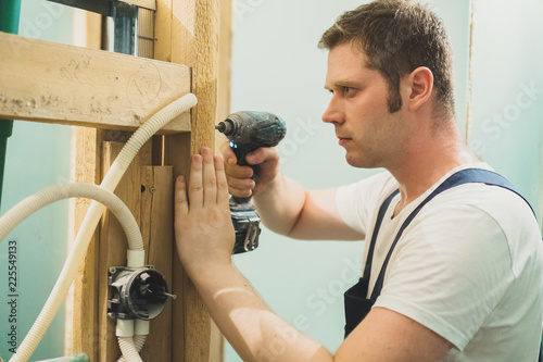 Handsome male worker unmounting an old wooden construction.