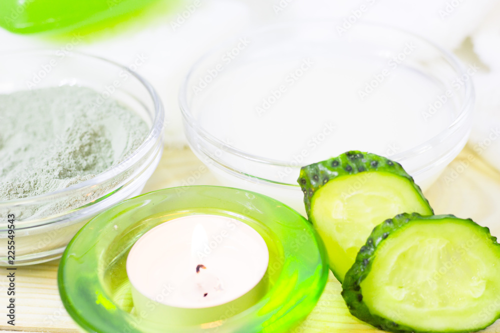 Cucumber home spa and hair care concept. Sliced cucumber, bottles of oil, sea salt, candle, bathroom towel. White board background Cucumber home spa and hair care concept. Sliced cucumber, bottles of oil, sea salt, candle, bathroom towel. White board background
