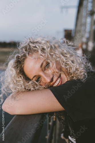 Portrait of smiling woman with bleached hair leaning on railing