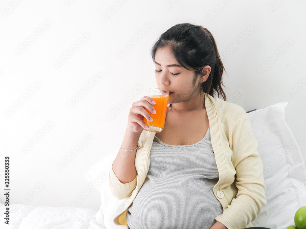Asian pregnant woman drinking a glass of orange juice, lifestyle concept. Asian pregnant woman drinking a glass of orange juice, lifestyle concept.