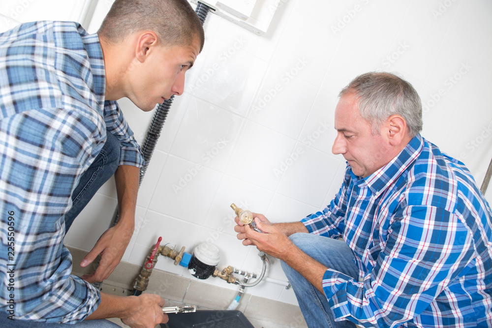two male plumbers working on pipework two male plumbers working on pipework