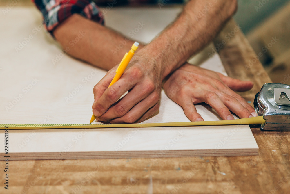 craftsman measuring with ruler and pencil on a wood board craftsman measuring with ruler and pencil on a wood board