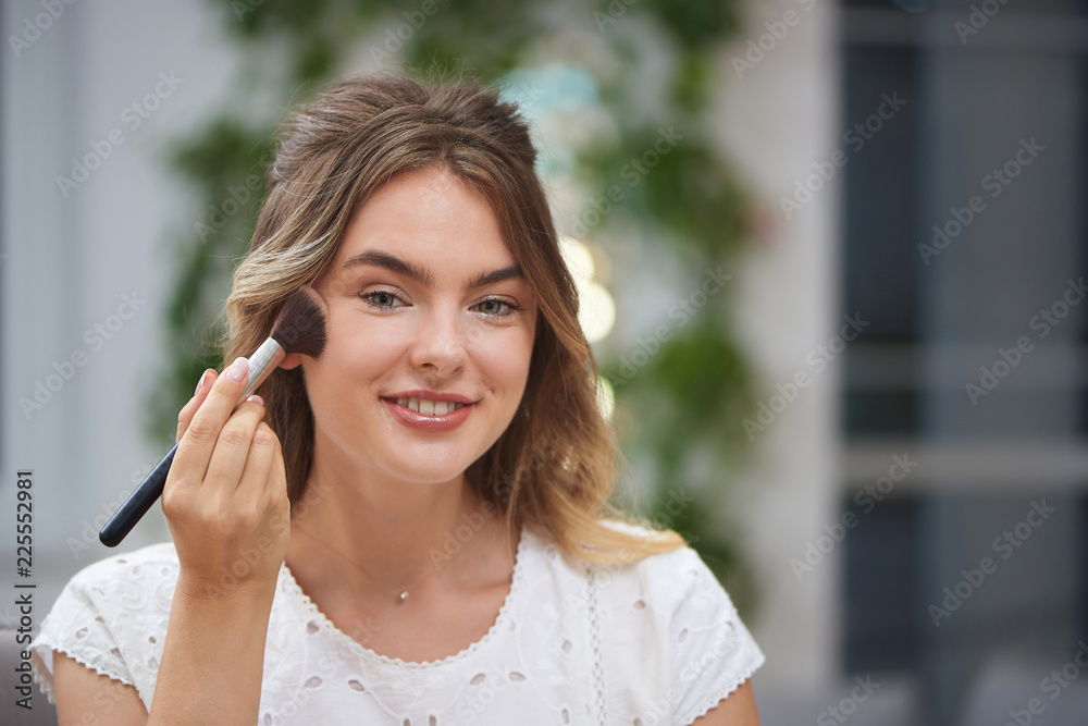 Front view of woman correcting makeup in salon Front view of woman correcting makeup in salon