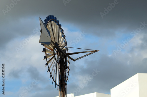 Old rusty and vintage wind mill or water pump with grey sky background