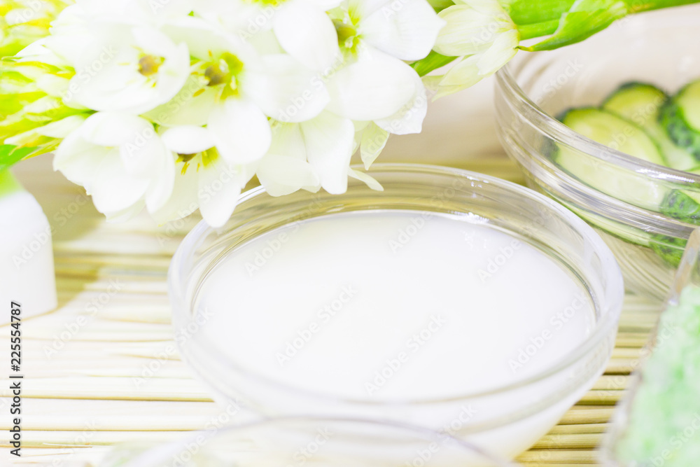 Cucumber home spa and hair care concept. Sliced cucumber, bottles of oil, bathroom towel. Straw light background