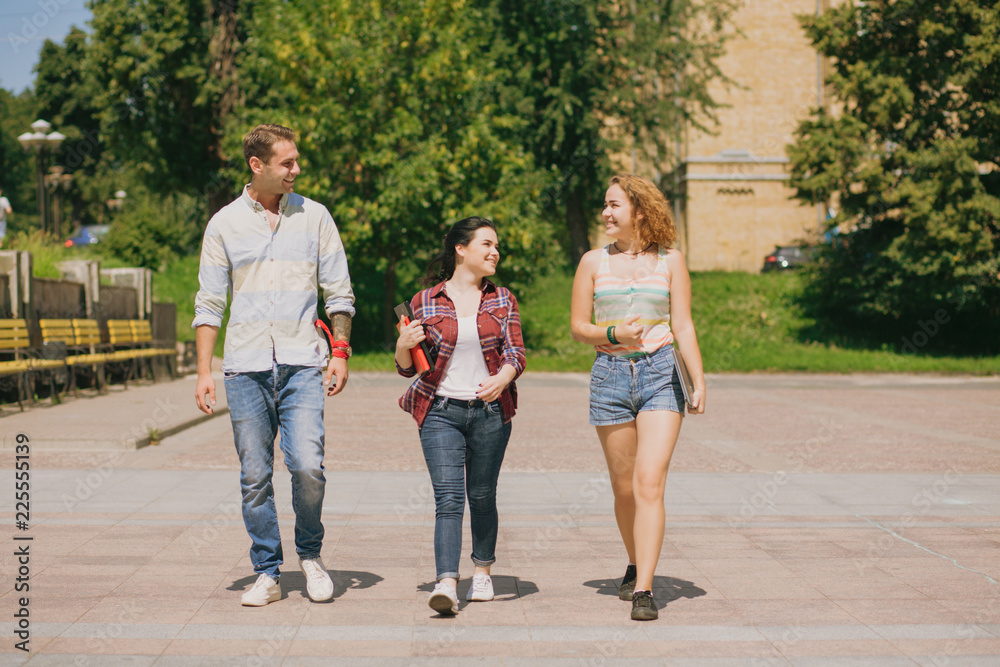 Three students walking in the park. Happy teens having conversation. Three students walking in the park. Happy teens having conversation.