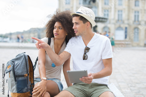 young couple of tourists looking at tablet screen outdoors photo
