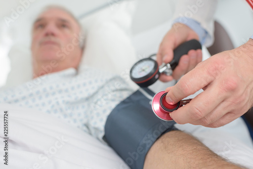doctor checking old man patient arterial blood pressure
