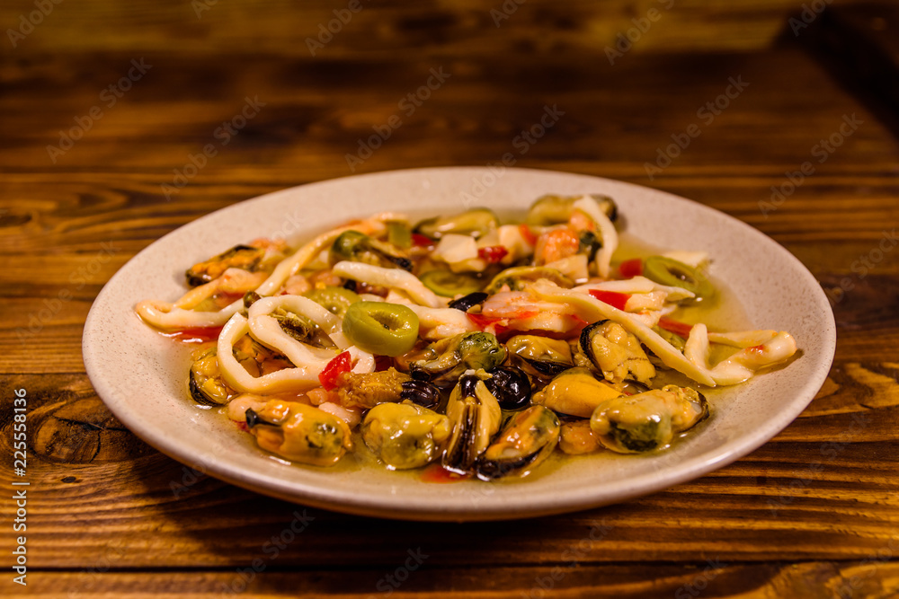 Ceramic plate with different sea food and olives on wooden table Ceramic plate with different sea food and olives on wooden table