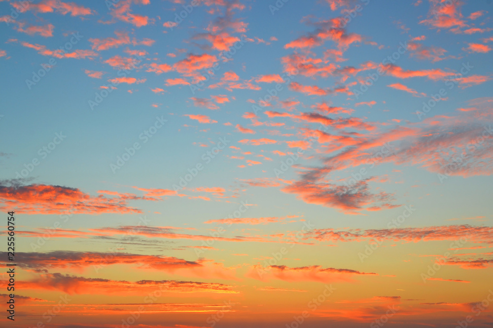 Pink and orange clouds on a blue sky at dawn just before sunrise background