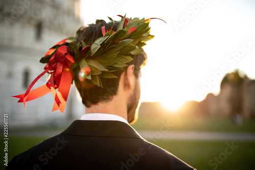 Photography Giovane ragazzo laureato con corona d'alloro in testa e vestito elegante visto di spalle