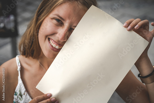 Junge lächelnde Frau hält leeres Papier 