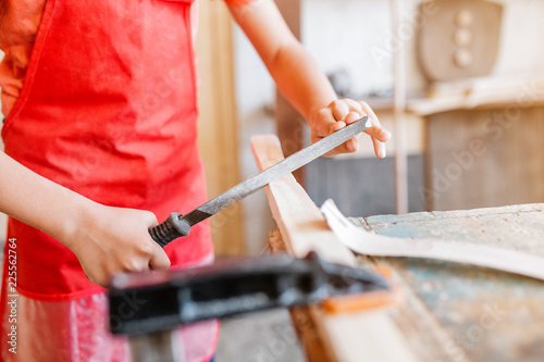 Little talented genius boy works with wood in a carpentry workshop. The concept of learning, hobbies and manual hand work for children