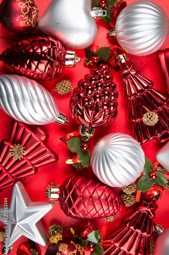 A top view of  mixed silver, red and green christmas ornaments on red background