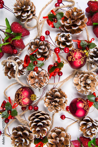 A top view of  mixed christmas ornaments: glazed pine cones, red  balls and berries on white background