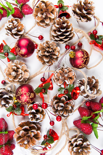 A top view of  mixed christmas ornaments: glazed pine cones, red  balls on white background
