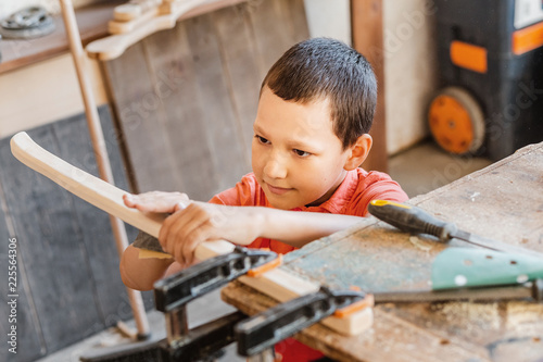 Vászonkép Little talented genius boy works with wood in a carpentry workshop