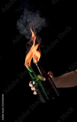 Molotov cocktail bottle with fire in the hand on a black background.