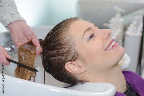 Hairdresser washing and combing customer's hair