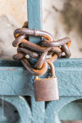 An old rusty chain lock closes the gate.