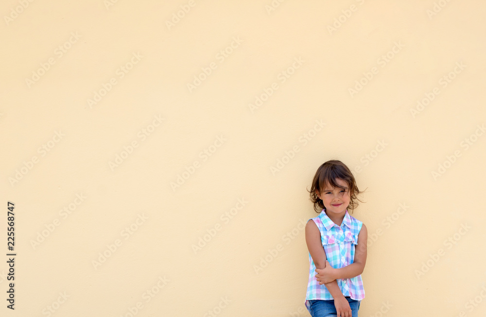 Little girl smiling and possing next to a yellow wall Little girl smiling and possing next to a yellow wall