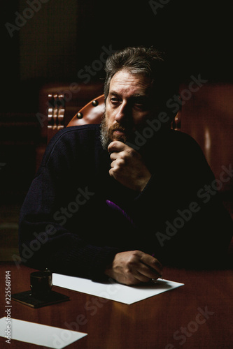 writer with beard writes on white sheet with goose feather