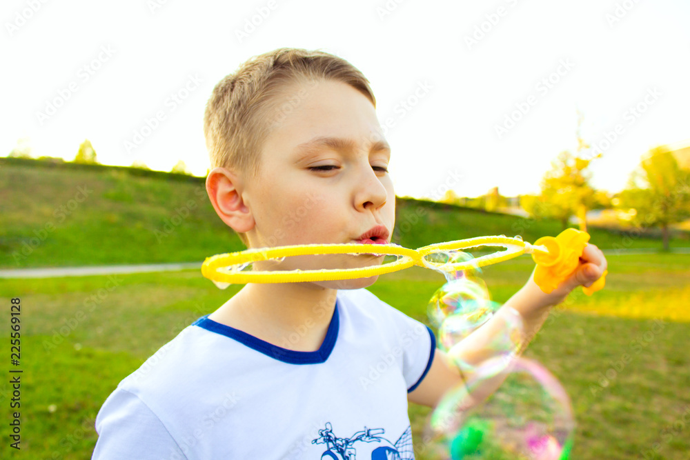 simpotichny cheerful boy with blond hair blows soap bubbles simpotichny cheerful boy with blond hair blows soap bubbles