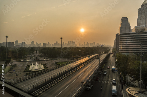 Sunrise Above The Bangkok City Skyline. High Buildings Behind a Park with Highway on Foreground © Oleksandr