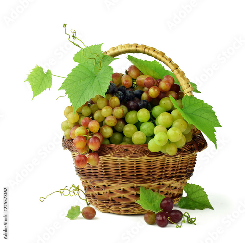 Basket of fragrant grapes isolated on white. Bunches of ripe grapes with leaves and tendrils. Autumn harvest. Close-up.