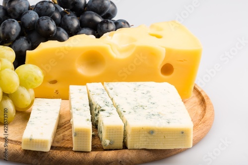 Cheeses and Grape on the Wooden Platter on the Grey Background