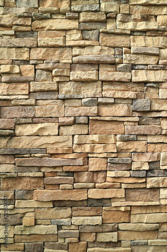 Vertical photo of brown and gray rough stone wall for background or banner 