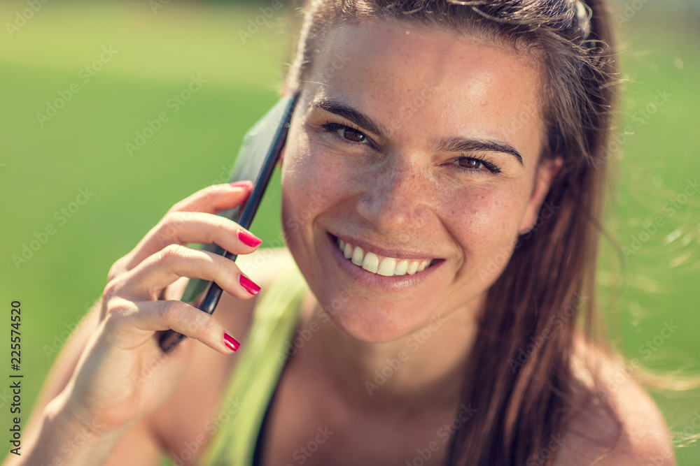 beautiful young sporty brunette relaxing in a park, stretching and looking at her phone beautiful young sporty brunette relaxing in a park, stretching and looking at her phone