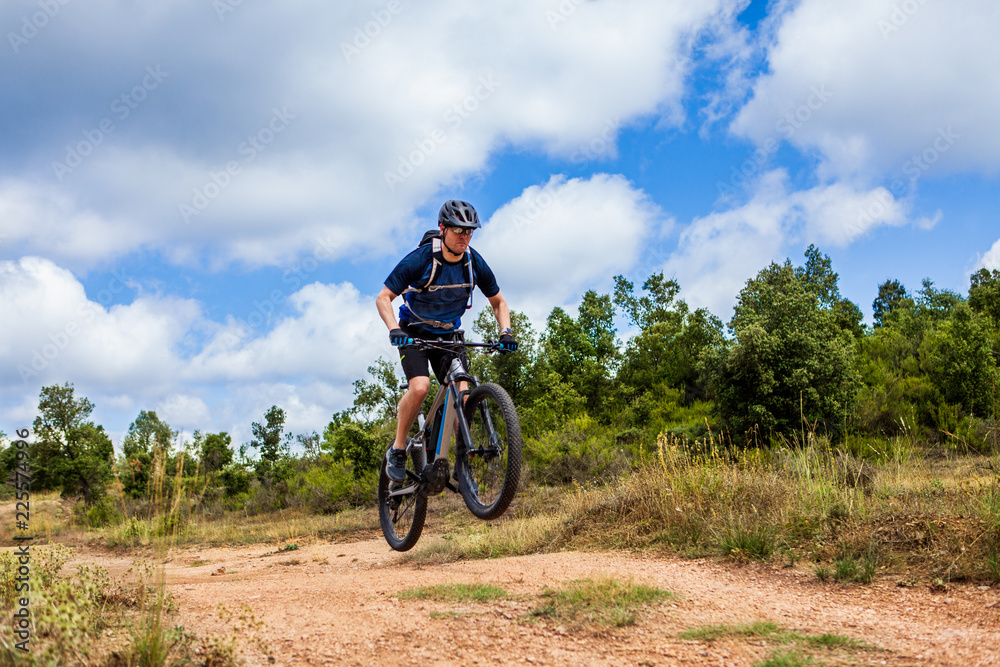 Male mountain biker does a bunny hop over small bump with his ebike Male mountain biker does a bunny hop over small bump with his ebike