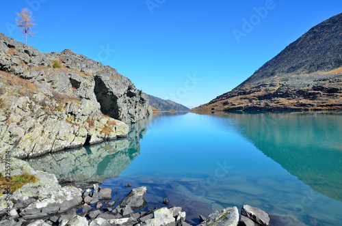 Россия, Республика Алтай, прозрачная вода и скалистые берега озера Акчан в безветренную погоду