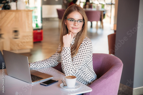 Young girl student in glasses make some design on laptop