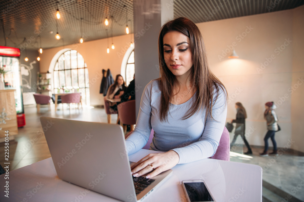 Business lady sitting in cafe and working on a laptop and using phone Business lady sitting in cafe and working on a laptop and using phone