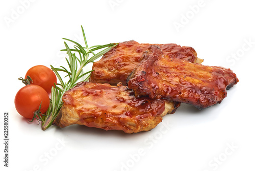 Delicious grilled pork ribs in BBQ sauce with herbs and tomatoes, isolated on white background. Close-up.